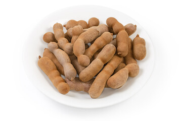 Ripe dry whole tamarind fruits on a white dish