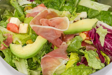 Vegetable salad with lettuce, avocado and jamon, fragment close-up