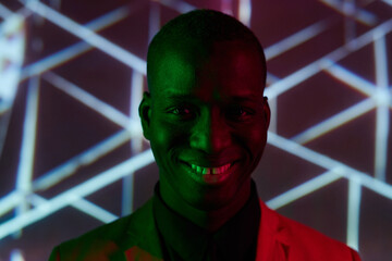 Happy young African man with toothy smile looking at camera while standing against creative background