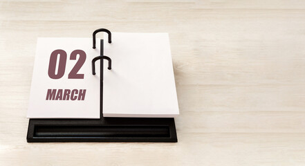 march 2. 2th day of month, calendar date. Stand for desktop calendar on beige wooden background. Concept of day of year, time planner, spring month