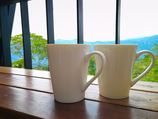 Two porcelain cups facing the mountain view and white sky