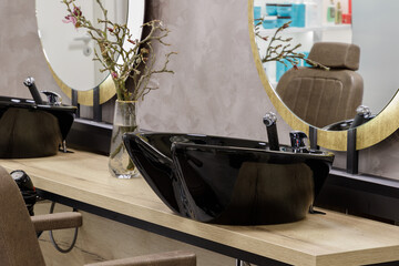 Luxury men's seat with a wooden table and black wash sink for washing hair