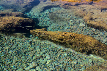 Fototapeta na wymiar Gran Canaria, calm rock pools under steep cliffs of the north coast are separated from the ocean by volcanic rocks of platform constructed by old lava flows Punta de Galdar area