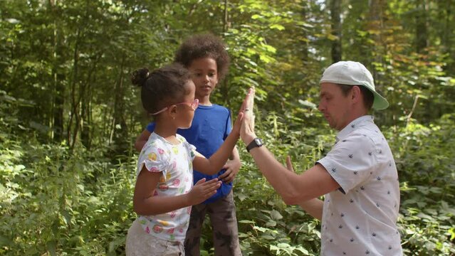 Father teaches children playing with hands. Patty Cake game is easiest hand-clapping games to start. Lifestyle, outdoor. 