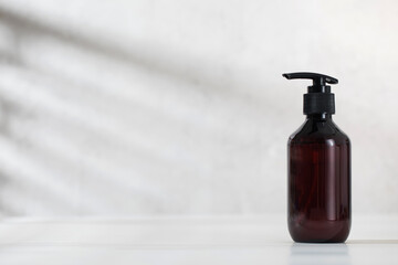 A mock-up of an organic cosmetic product in a brown dispenser on a light background with shadows. 