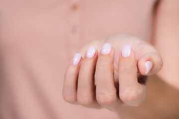 Closeup top view of elegant pastel pink natural manicure. Horizontal color photography of manicured...