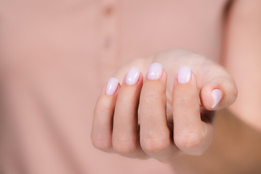 Closeup top view of elegant pastel pink natural manicure. Horizontal color photography of manicured female hands with holiday Valentines day or wedding nail design. Pink nails with white hearts