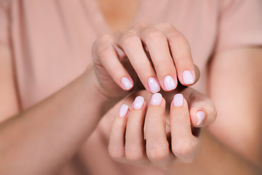 Closeup top view of elegant pastel pink natural manicure. Horizontal color photography of manicured female hands with holiday Valentines day or wedding nail design. Pink nails with white hearts