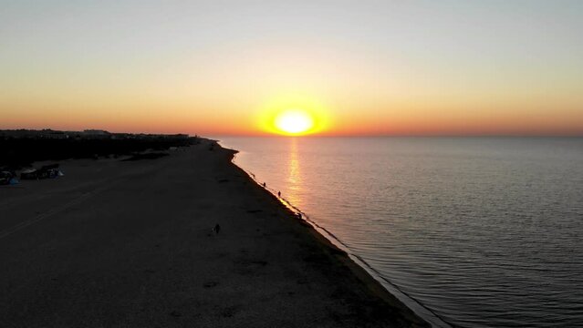 Drone shot Sunrise on the Black Sea in Zatoka. Sunrise Odessa. People walk by the sea at sunrise. The first rays of the sun on the sea in Odessa. Drone shot of Zatoka resort at sunrise