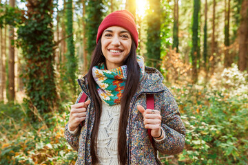Young cheerful beautiful hiker woman walking throught winter woodland - Hiking active female...