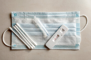 Covid testing kit on mask background. Positive result on Covid-19 rapid swab test. 