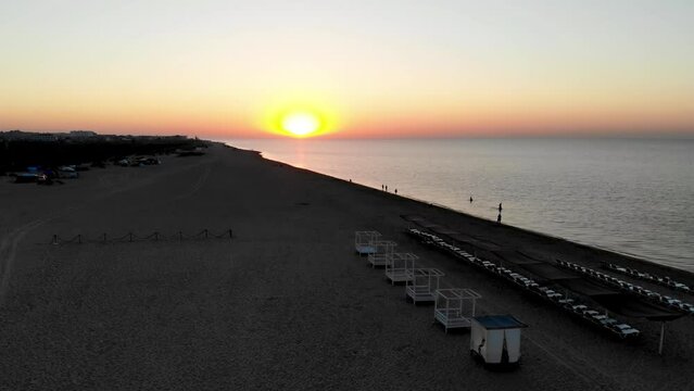 Drone shot Sunrise on the Black Sea in Zatoka. Sunrise Odessa. People walk by the sea at sunrise. The first rays of the sun on the sea in Odessa. Drone shot of Zatoka resort at sunrise
