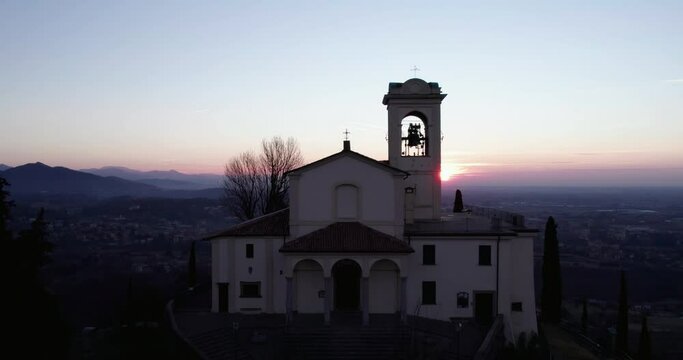 Rising aerial shot at sunrise in backlight condition with a sanctuary in foreground. Shot in Montevecchia, Brianza.
