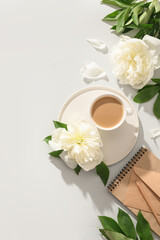 Obraz na płótnie Canvas Summer or spring breakfast with coffee, white peonies flowers, craft envelope on gray background with sunny shadow. Spring vertical workplace, top view, flat lay.