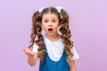 The surprised little girl stretched out her hand forward and asks. A child with long curly hair opened her mouth.