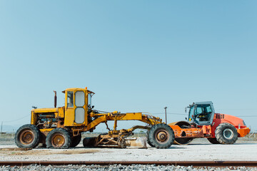 Orange and yellow excavators standing outdoor. Construction machines, transport