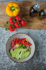 Plate of vegetable and avocado salad, olive oil and wine vinegar in bottles. Healthy food. Vegetarian. Tomatoes and green salad. Organic products. Eco. Home.