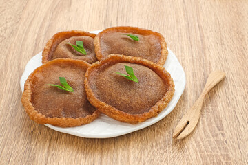 Kue Cucur is Indonesian traditional snack, made from rice flour and palm sugar and then fried. Served on white plate on wooden background. Selected focus.

