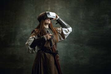 Portrait of young wman, medieval warrior, knight with long hair in VR headset isolated over dark...