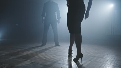 Legs of tango dancers in dark smoky studio. Woman goes to man. Woman legs on heels. Close-up shot in 4K, UHD