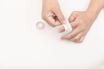 Man's finger is bandaging a gauze bandage wound from knife cut on white table background Hemostasis and first aid for injured persons