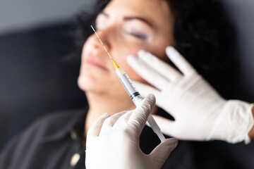 Plastic surgery clinic. Hands of cosmetologist making botox injection holding Syringe. Concept of...
