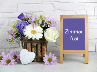 Tafel mit dem Text Zimmer frei ,mit Blumenstrauß und Herz
