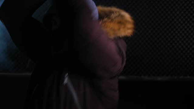 A man in a black mask and hood strikes several blows with a bat in the smoke at night. Assault, fight, robbery