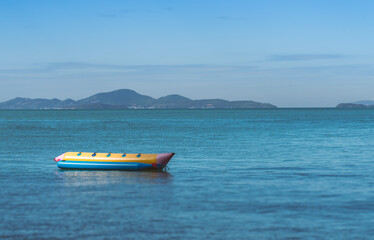 Lonely Banana boat is floating in the sea at Pattaya of Thailand, no people, view background of mountainscape and sky, blank space for text and design.