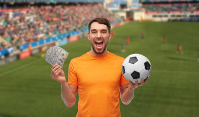 sport, leisure games and online betting concept - happy smiling man or football fan with soccer ball and money over stadium background