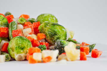 A mixture of frozen vegetables in a pile. Preparation for a dish on a white background.