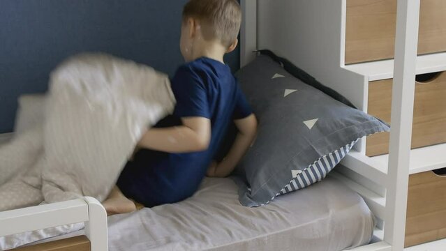 Boy scratches body with chickenpox papules. The child has chickenpox and is sitting on bed in children room.