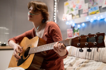 Sick girl sitting at hospital bed and playing guitar at the ward during her treatment at pandemic...