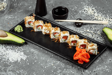 sushi rolls with cream cheese, fried salmon, tuna shavings or dried bonito, cucumber, nori. Chopsticks holding fresh katsuobushi roll in Japanese restaurant closeup
