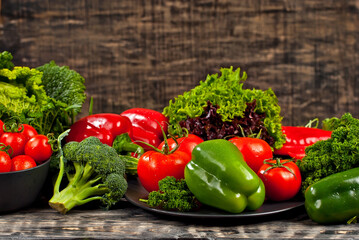 Cabbage, peppers, tomatoes, cucumbers, lettuce, cherry tomatoes, broccoli, arugula on a black background. variety of vegetables on a pile on a wooden table.
