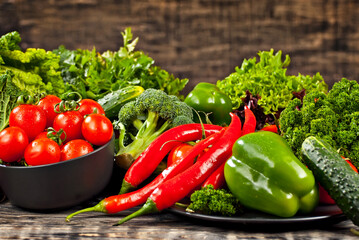 Cabbage, peppers, tomatoes, cucumbers, lettuce, cherry tomatoes, broccoli, arugula on a black background. variety of vegetables on a pile on a wooden table.