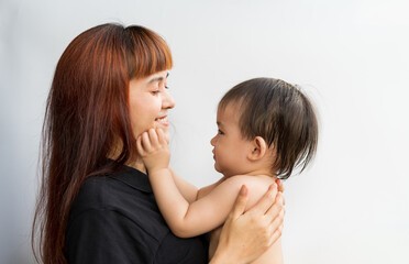 Happy mother with her baby on isolated white background. Mom and son tease each other sweetly and tenderly cheerful smiling merrily. Young attractive happy mother hugging looking at her littel baby.