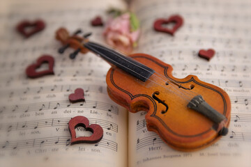 miniature wooden hearts and violin on a musical score 
