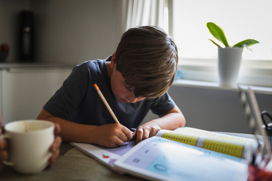 Boy writing in book while studying at home