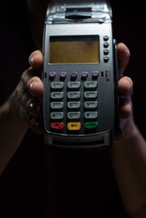Credit card reader isolated on black background. Pos apparatus for non-cash contactless payment. A man holds an NFC terminal in his hands.