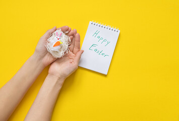 Fototapeta na wymiar hands holding a happy easter card with easter bunny on yellow background.