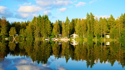 Wunderschöner Blick auf Stukas Ferienhäuser vom See aus in Schweden mit Spiegelungen im Wasser vom Boot aus Im Schwedenurlaub