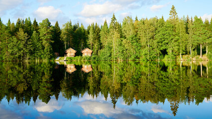 Wunderschöner Blick auf Stukas Ferienhäuser vom See aus in Schweden mit Spiegelungen im Wasser...