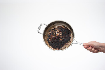 Dirty oily burnt metal frying pan held in hand by male hand