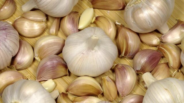 Fresh garlic bulbs and cloves on a wooden table, rotation background. Loop motion