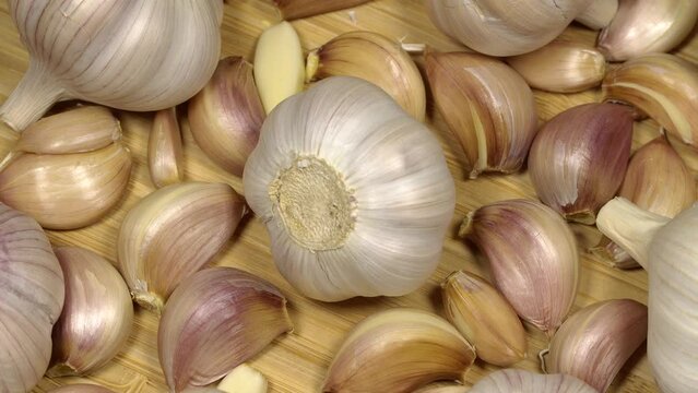 Fresh garlic bulbs and cloves on a wooden table, rotation background. Loop motion