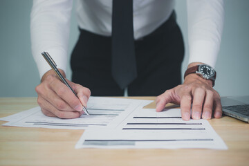 Businessman signing documents, analyzing data in office