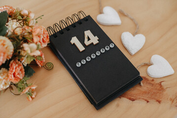 Wooden calendar on February 14 with roses and heart.