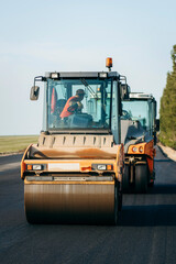 Vibratory asphalt roller compactor compacting new asphalt pavement. Road service repairs the highway