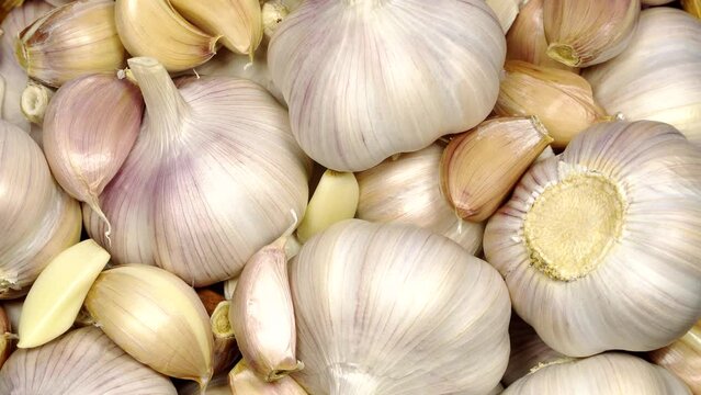 Fresh garlic bulbs and cloves on a wooden table, rotation background. Loop motion